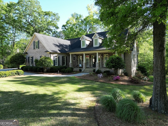 cape cod house featuring covered porch and a front yard