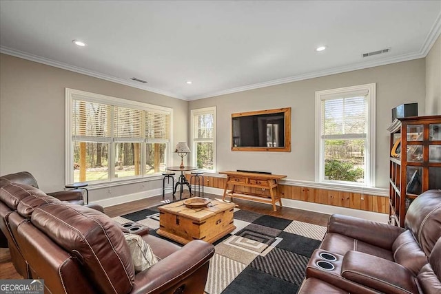 living room with wood finished floors, visible vents, and crown molding