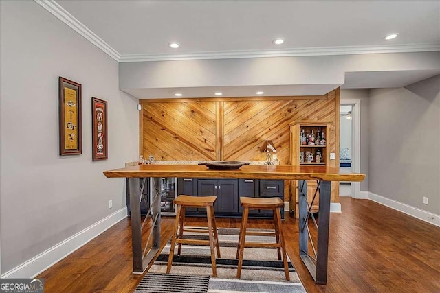 bar with wood finished floors, a dry bar, baseboards, and ornamental molding