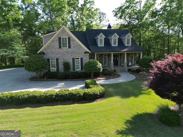 cape cod home with a chimney, a front lawn, and a porch
