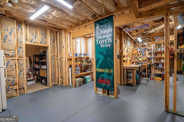 unfinished below grade area with freestanding refrigerator and a workshop area
