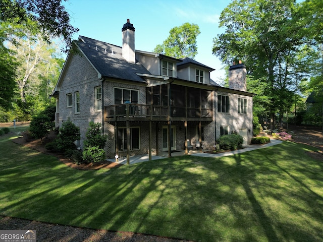rear view of house with a patio area, a chimney, a sunroom, and a yard