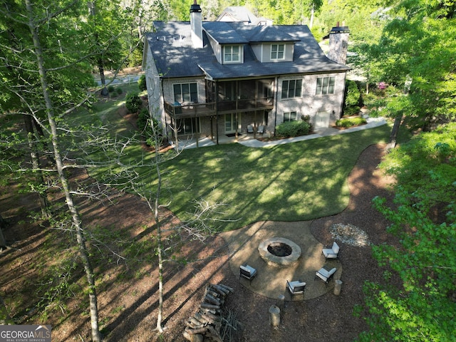 back of house featuring a chimney, a wooden deck, a fire pit, and a patio area