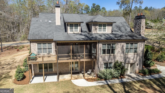 back of house with brick siding, a chimney, a patio, and a shingled roof