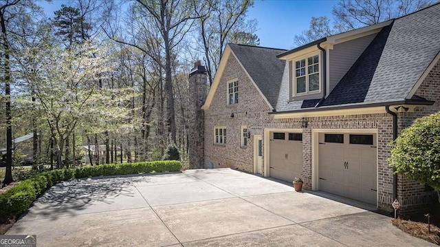 view of home's exterior with a garage, roof with shingles, brick siding, and driveway