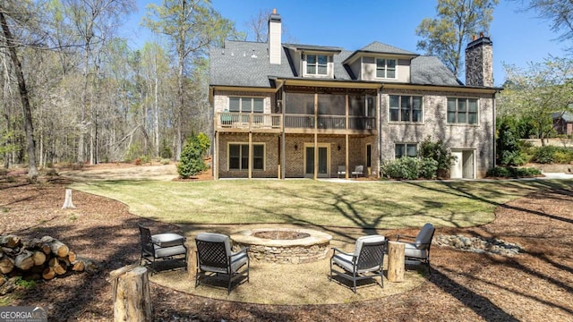 back of property featuring an outdoor fire pit, a yard, a patio, and a sunroom