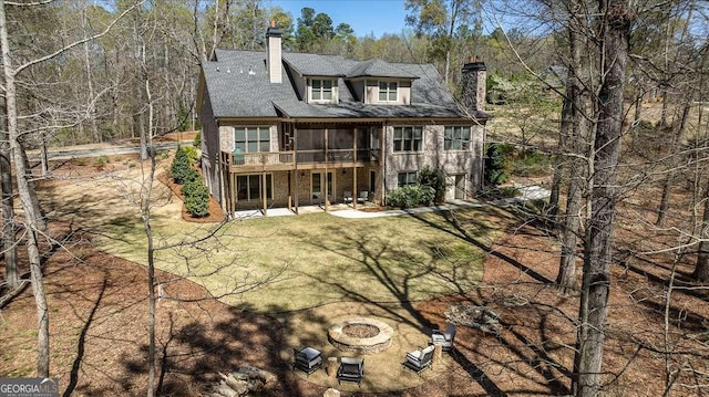 back of property with an outdoor fire pit, a patio, and a lawn