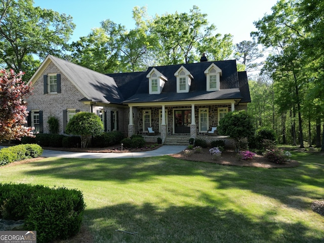 cape cod home with a porch, stone siding, a chimney, and a front yard