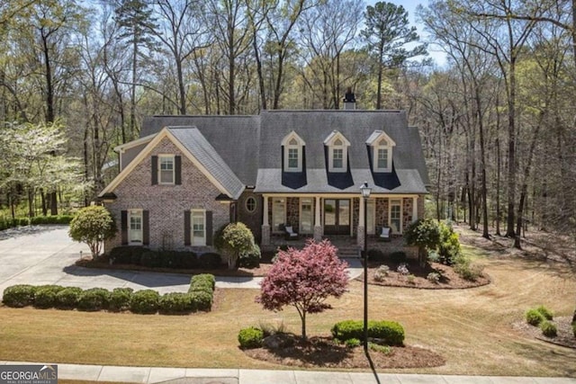 cape cod house with a front yard and covered porch