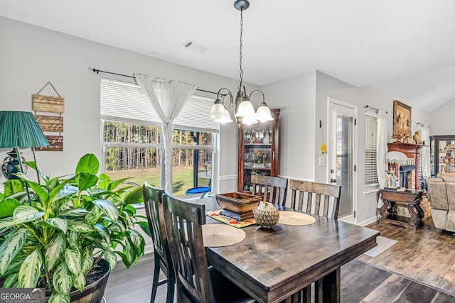 dining area with an inviting chandelier, hardwood / wood-style flooring, and lofted ceiling