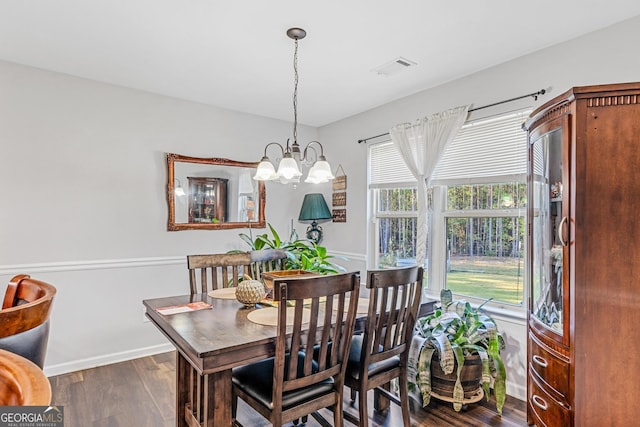 dining room with dark wood-type flooring and a notable chandelier