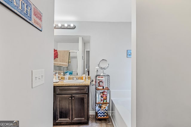 bathroom with hardwood / wood-style flooring, vanity, and a tub to relax in