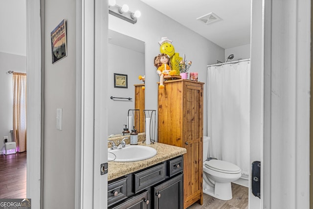 bathroom featuring vanity, hardwood / wood-style flooring, toilet, and walk in shower