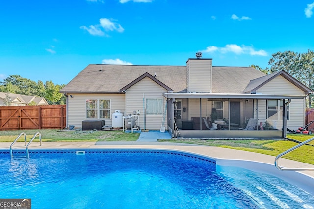 back of property featuring a fenced in pool, a yard, and a sunroom