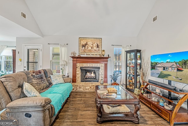 living room with a healthy amount of sunlight, hardwood / wood-style floors, and a brick fireplace