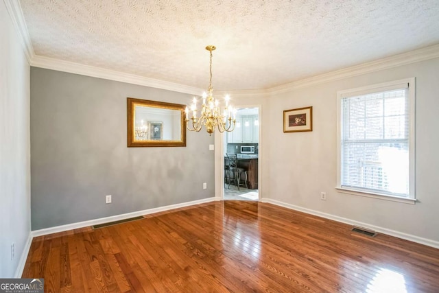 unfurnished dining area with hardwood / wood-style floors, crown molding, a chandelier, and a textured ceiling