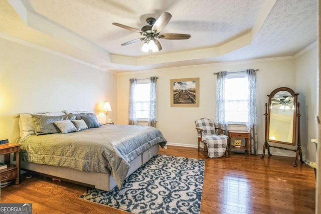 bedroom with crown molding, a tray ceiling, dark hardwood / wood-style flooring, and a textured ceiling