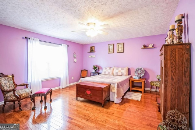 bedroom with ceiling fan, a textured ceiling, and light wood-type flooring