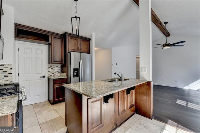 kitchen featuring appliances with stainless steel finishes, hanging light fixtures, light stone counters, lofted ceiling with beams, and kitchen peninsula