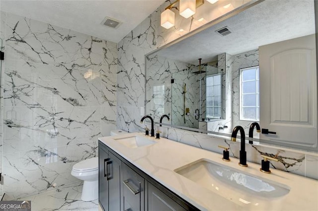 bathroom with tile walls, vanity, a textured ceiling, a shower with shower door, and toilet