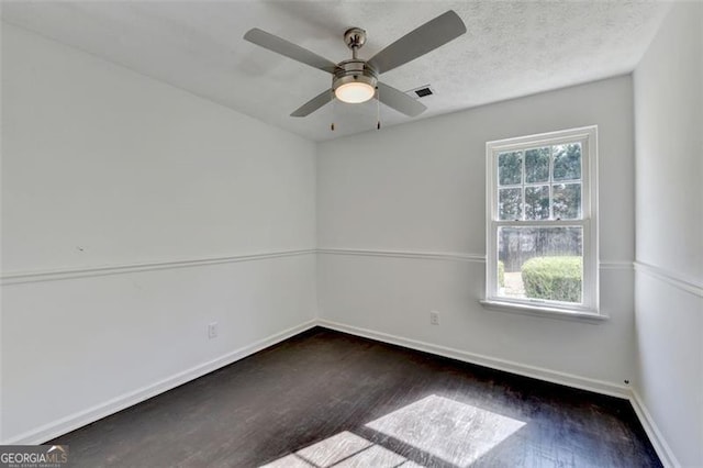 empty room featuring ceiling fan, dark hardwood / wood-style flooring, and a textured ceiling