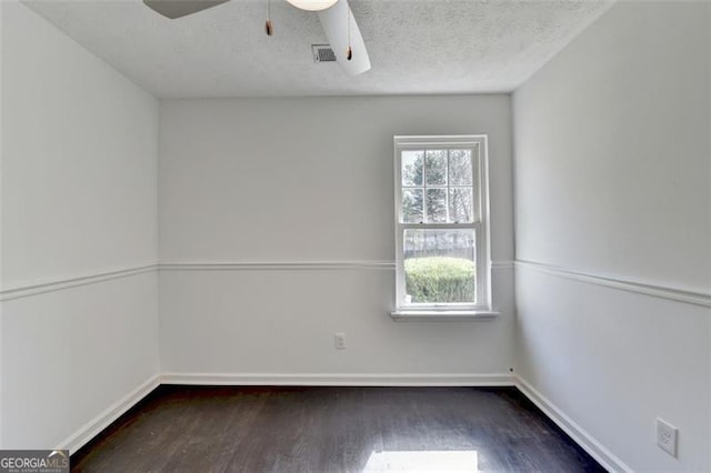 spare room featuring a textured ceiling, dark wood-type flooring, and a healthy amount of sunlight