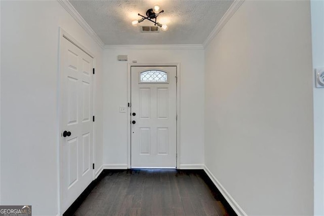 foyer entrance with dark wood-type flooring, ornamental molding, and a textured ceiling