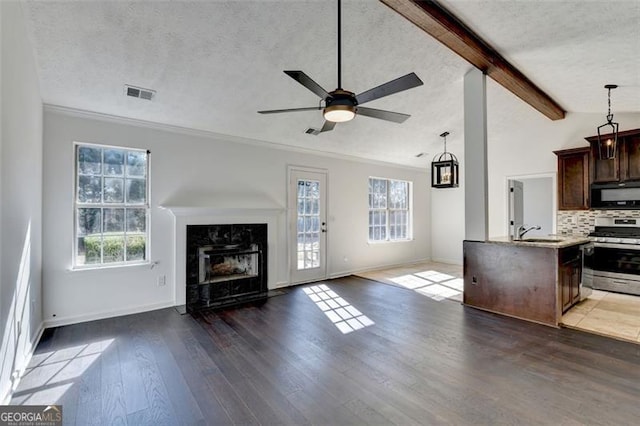 kitchen with stainless steel gas range, dark hardwood / wood-style floors, lofted ceiling with beams, a textured ceiling, and decorative backsplash