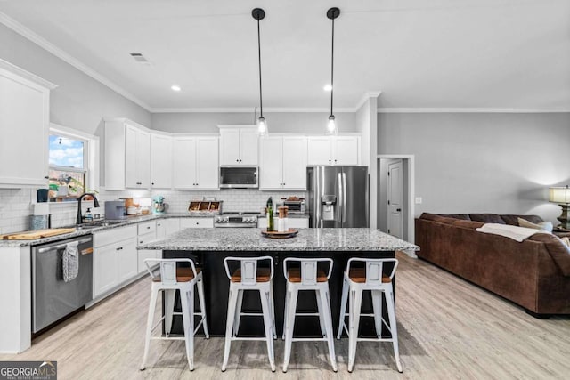 kitchen with pendant lighting, stainless steel appliances, a center island, and white cabinets