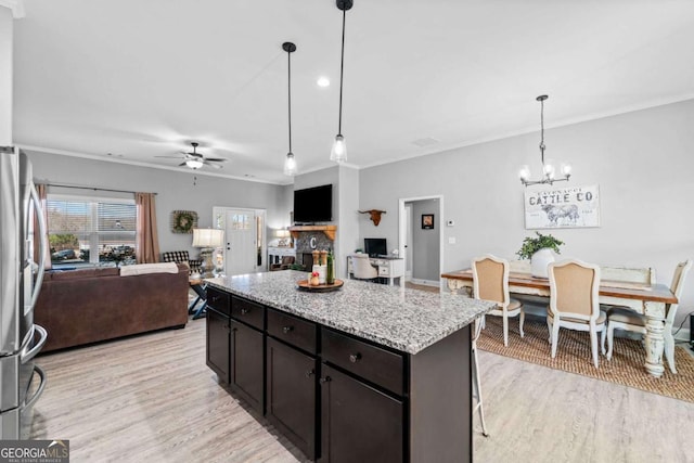 kitchen with crown molding, stainless steel fridge, hanging light fixtures, light hardwood / wood-style floors, and a kitchen island