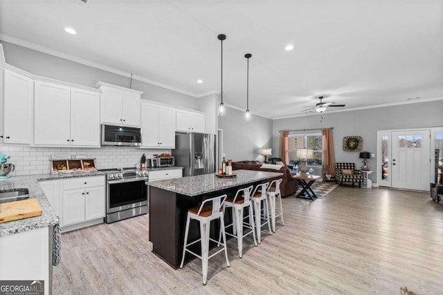 kitchen with a kitchen island, white cabinetry, appliances with stainless steel finishes, and pendant lighting