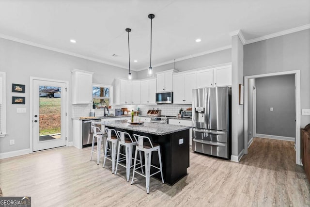 kitchen with stainless steel appliances, decorative light fixtures, a kitchen island, and white cabinets