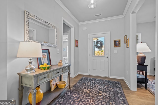 foyer entrance with ornamental molding and light hardwood / wood-style floors