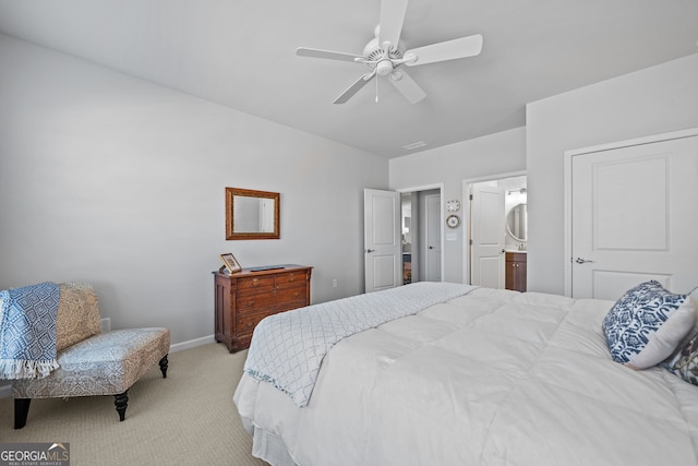 bedroom featuring ceiling fan, light colored carpet, and connected bathroom