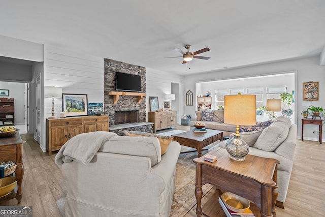 living room with ceiling fan, a fireplace, and light hardwood / wood-style flooring