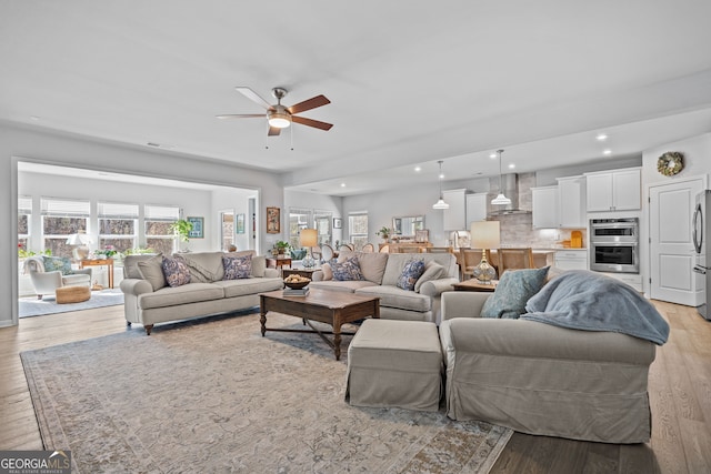 living room with ceiling fan, a healthy amount of sunlight, and light wood-type flooring