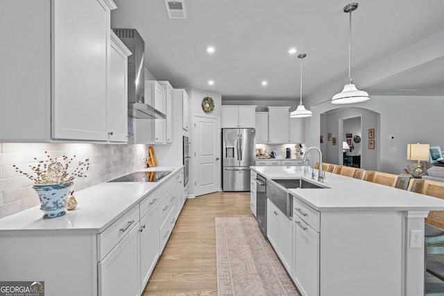 kitchen with sink, a breakfast bar, hanging light fixtures, stainless steel appliances, and white cabinets