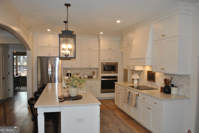 kitchen with white cabinetry, premium range hood, appliances with stainless steel finishes, and pendant lighting