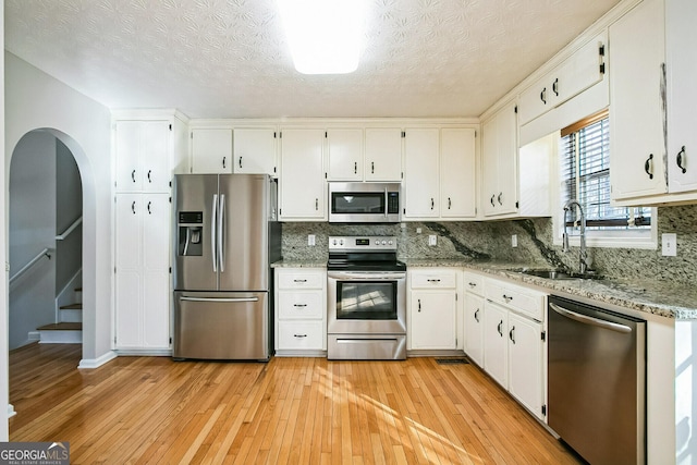 kitchen with light stone counters, sink, white cabinetry, and appliances with stainless steel finishes