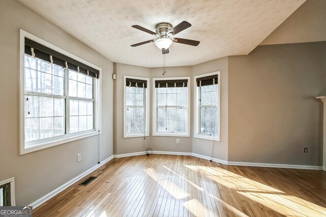 spare room with ceiling fan, a textured ceiling, and light wood-type flooring