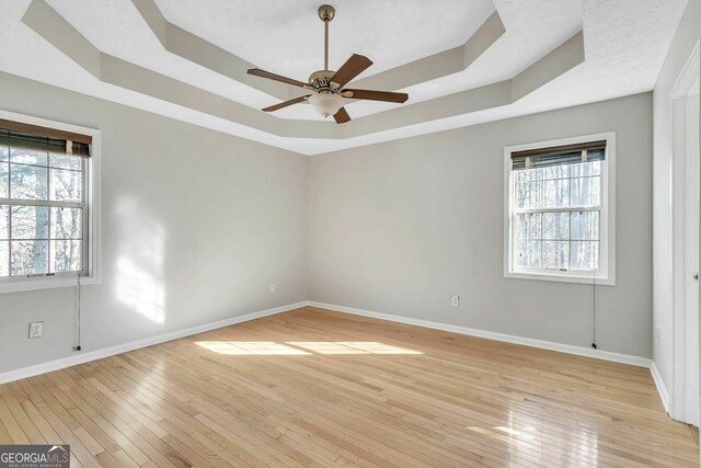 unfurnished room with a tray ceiling, light hardwood / wood-style flooring, and ceiling fan