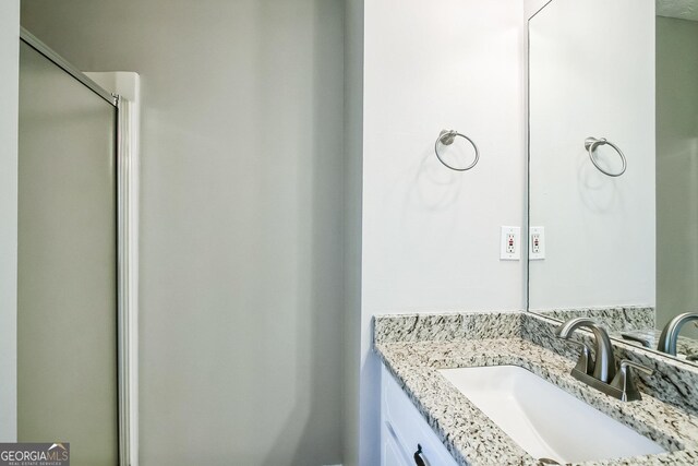 bathroom featuring walk in shower and vanity