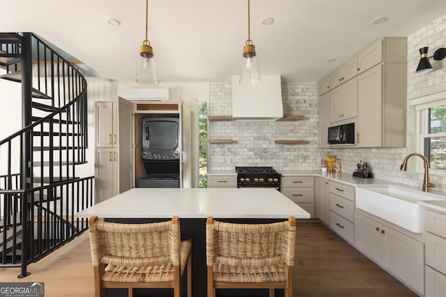 kitchen with stacked washer and clothes dryer, sink, decorative backsplash, and black appliances