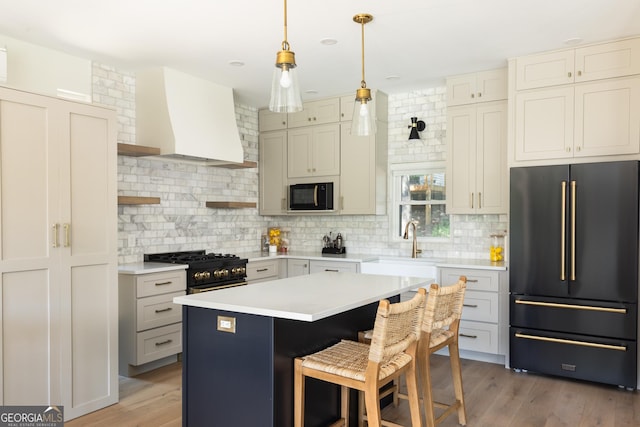 kitchen with wall chimney range hood, a breakfast bar area, a center island, tasteful backsplash, and black appliances