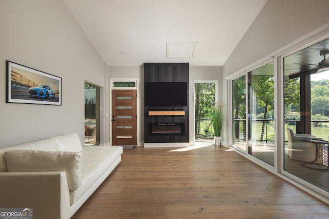 interior space with ceiling fan, a large fireplace, lofted ceiling, and hardwood / wood-style floors