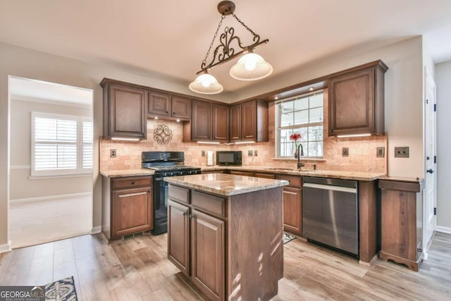 kitchen with light wood-type flooring, hanging light fixtures, a kitchen island, and black appliances