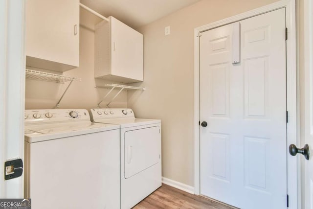 laundry area featuring cabinets, independent washer and dryer, and light hardwood / wood-style flooring