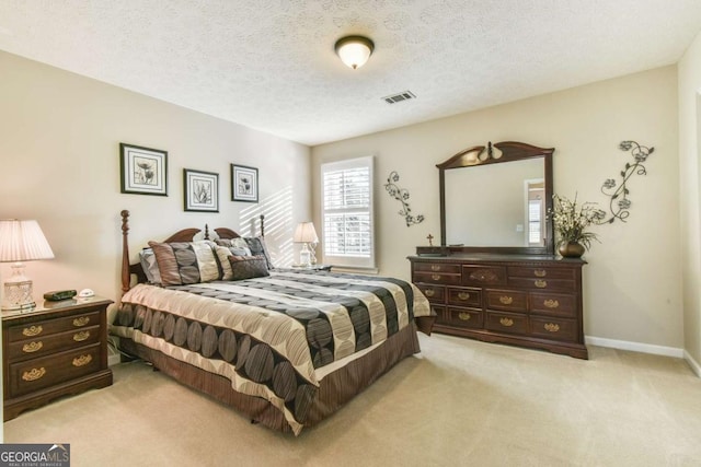 bedroom with light colored carpet and a textured ceiling