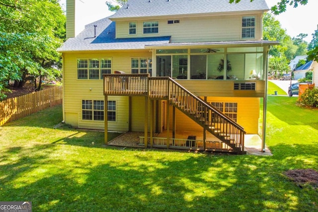 back of house with a sunroom, a deck, and a lawn