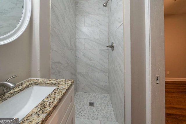 bathroom featuring hardwood / wood-style flooring, vanity, and tiled shower